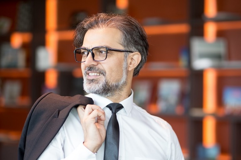 Closeup portrait of smiling middle-aged handsome business man looking away and holding jacket over shoulder